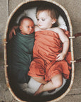Newborn and toddler resting together in a woven basket