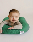 Smiling baby doing tummy time on a Moss green lounger cover
