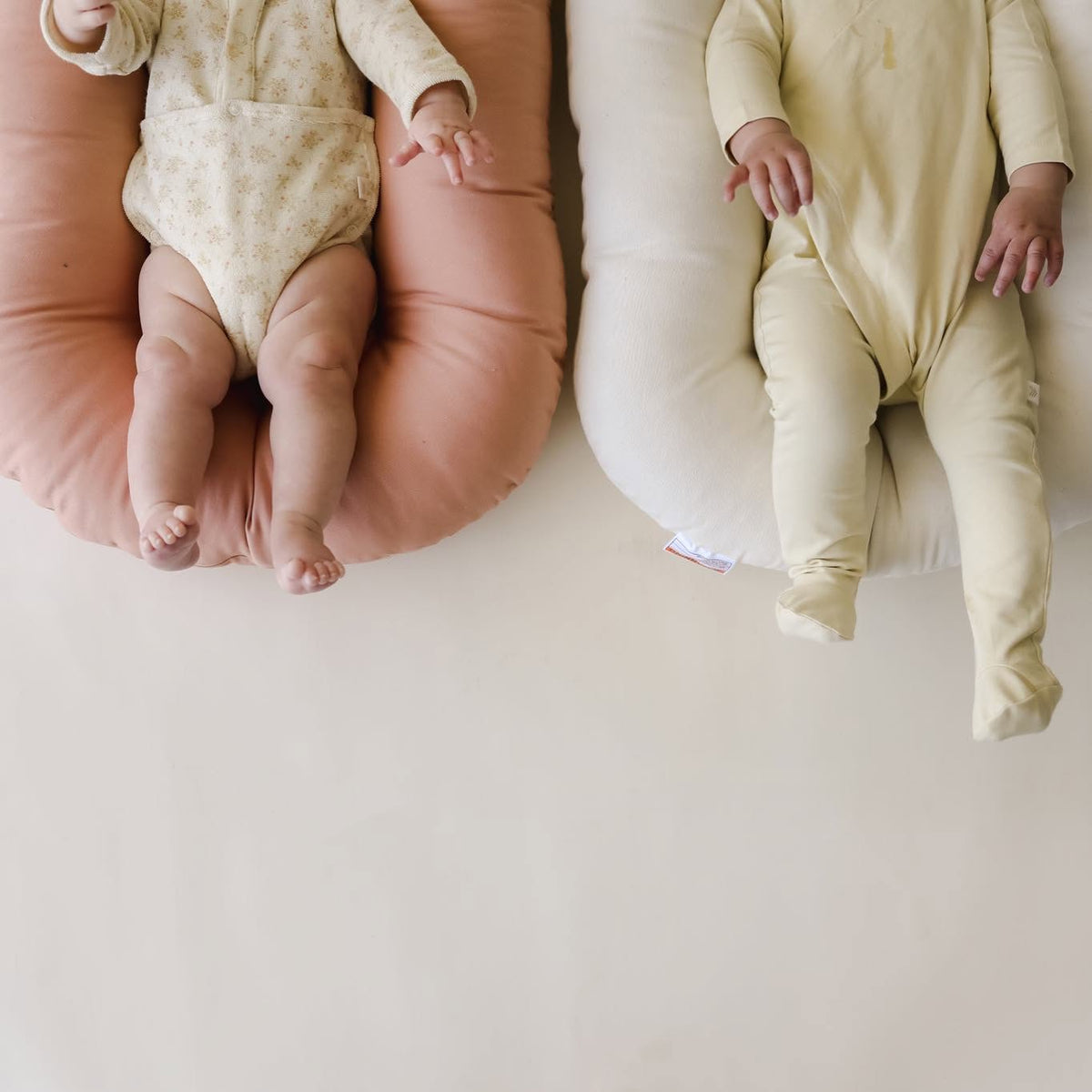 Babies' legs resting on Gumdrop and Natural organic lounger covers, top view