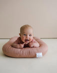Baby doing tummy time on a lounger with a Gumdrop pink cover
