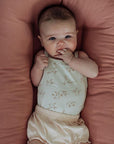 Baby lying in a Gumdrop pink lounger with hand in mouth, top view