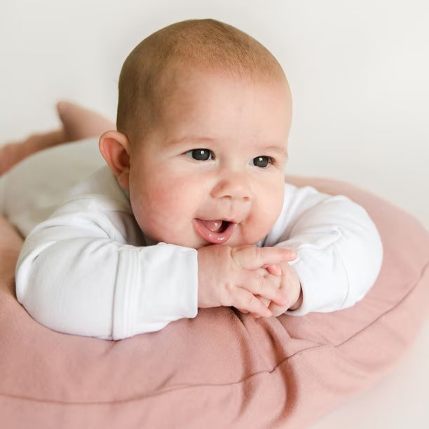 Baby doing tummy time over the side of a Gumdrop infant lounger