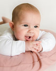 Baby doing tummy time over the side of a Gumdrop infant lounger