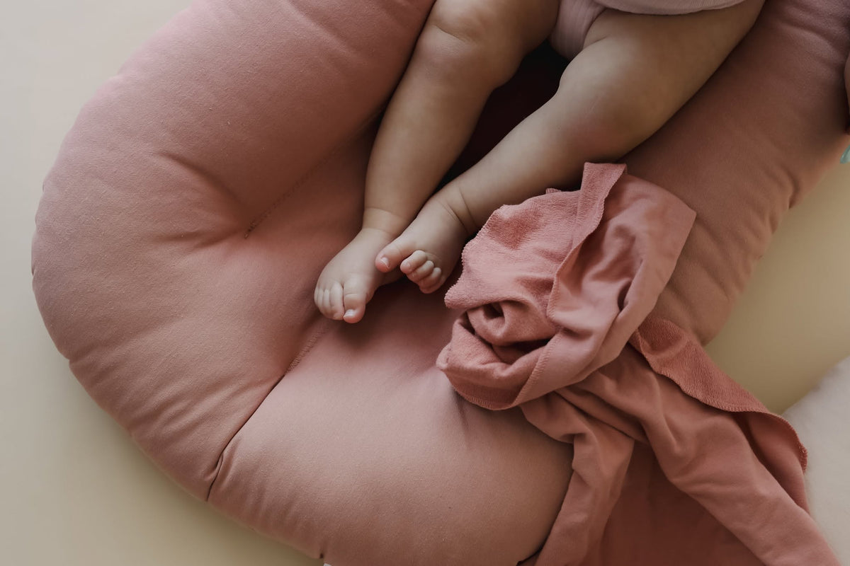 Close-up of baby feet on a Gumdrop pink organic cotton lounger cover