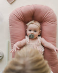 Baby with a pacifier lying in a lounger with a Gumdrop pink cover