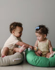 Two babies sitting in Birch and Moss green infant loungers, playing together