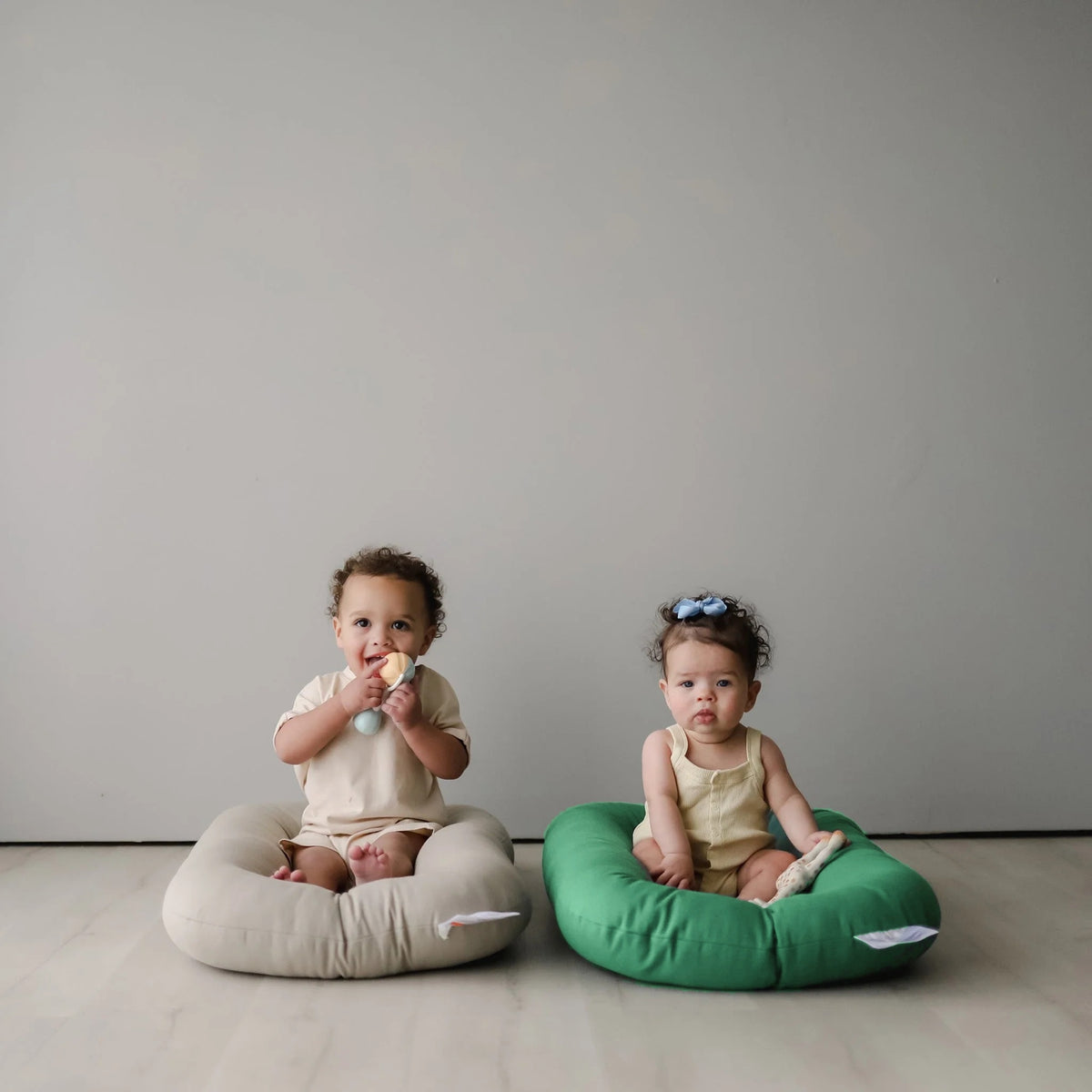 Two babies sitting side by side in Birch and Moss organic baby loungers