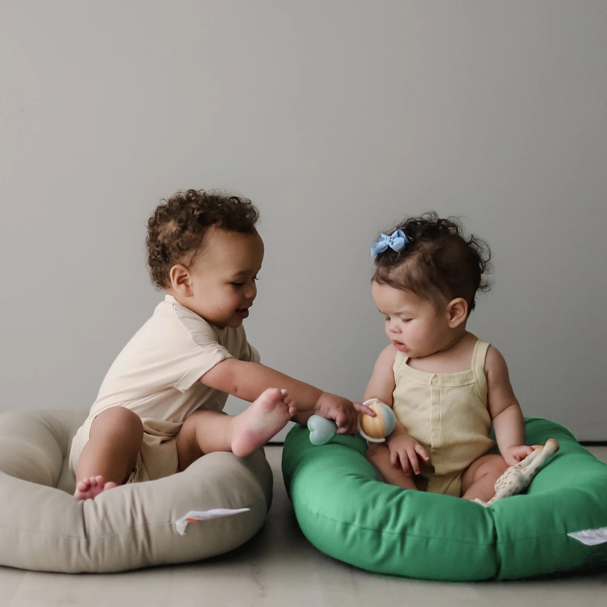 Babies playing in Moss and Birch organic cotton loungers, close-up