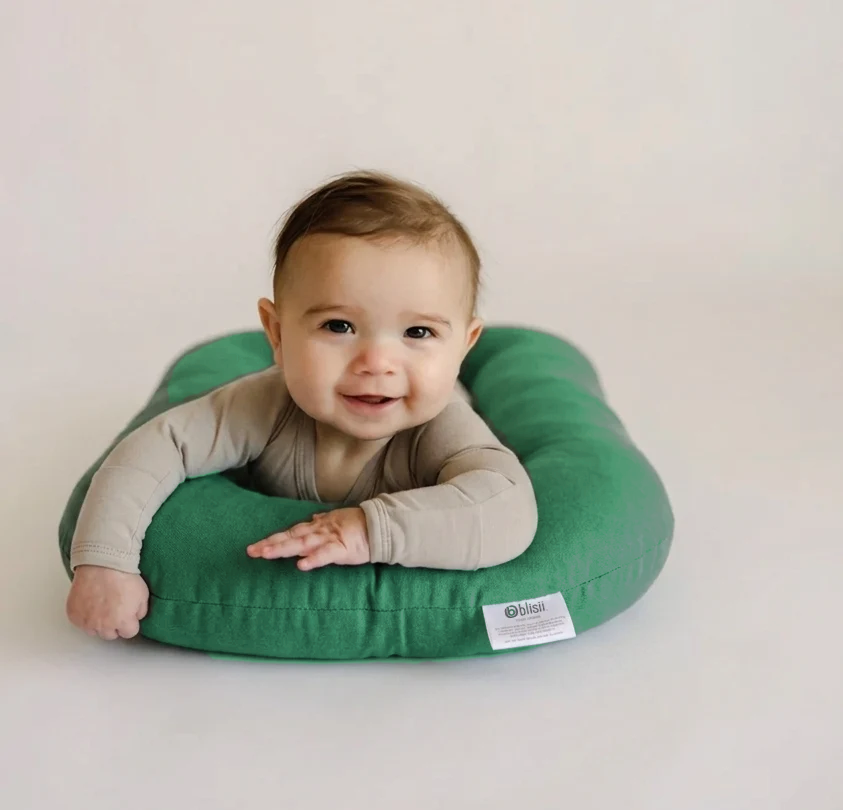 Smiling baby doing tummy time on a Moss green lounger cover